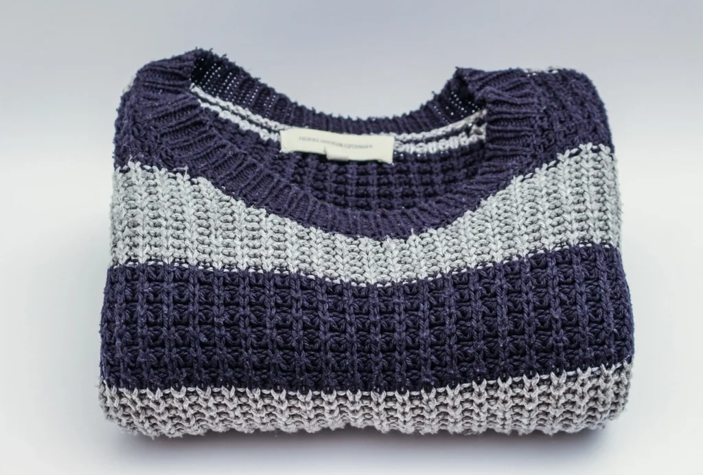 The Art of the Knit: Why a Textured Striped Sweater is Your New Wardrobe Essential navy grey striped knit sweater folded